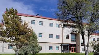 An exterior photo of the Jones Hall Annex building. Trees can be seen in the foreground, while blue sky and clouds are visible past the building.